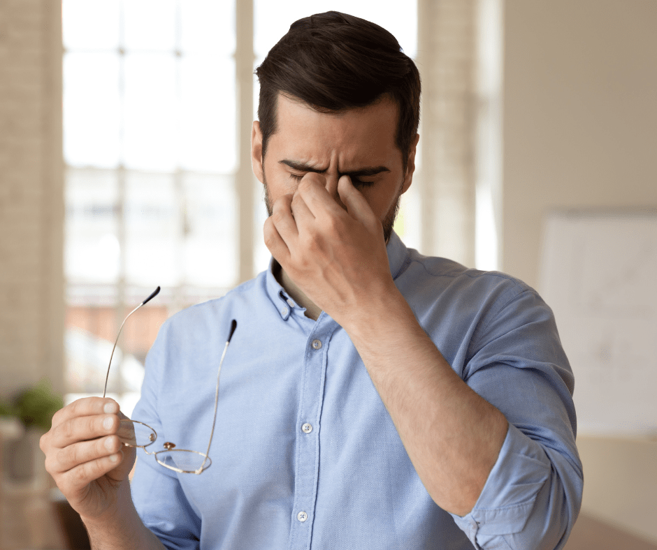 Stressed man pinching bridge of nose